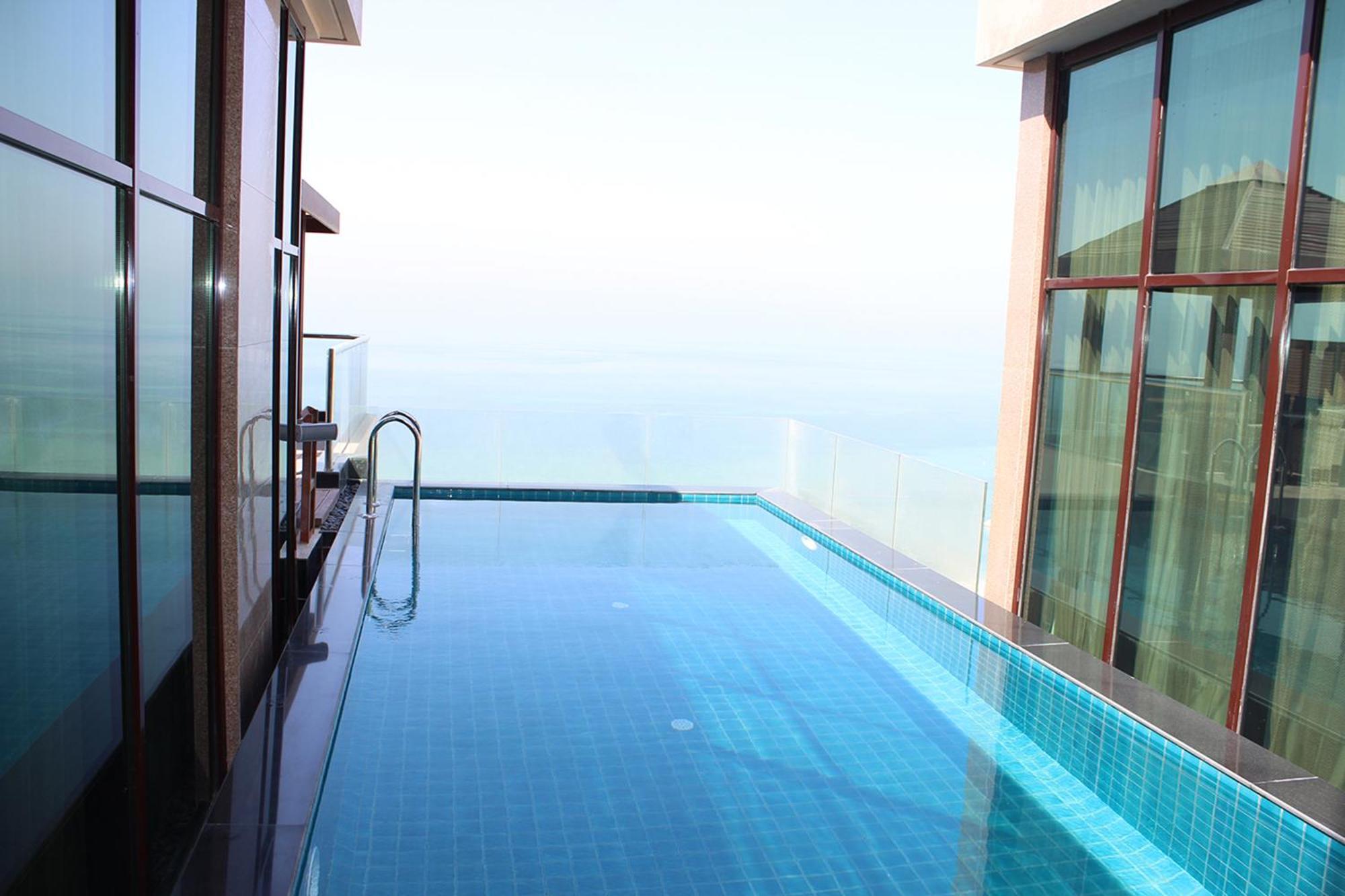 Lagoona Beach Luxury Resort And Spa Al Manamah Esterno foto The photo shows an infinity pool situated on a balcony or rooftop, with a clear view extending to the horizon. The pool has a sleek design with blue tiles, and it appears to be reflecting the sky. There is a ladder on one side for access into the poo