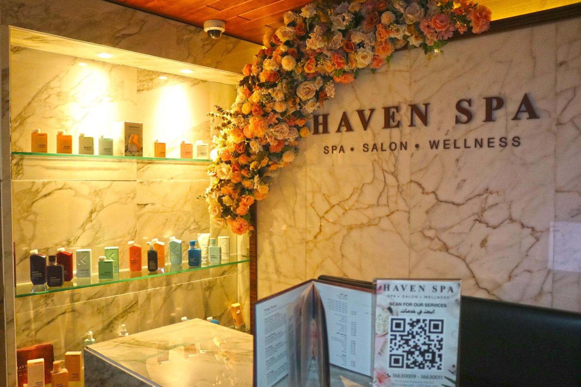 Lagoona Beach Luxury Resort And Spa Al Manamah Esterno foto The photo shows the interior of a spa called "Haven Spa." The wall is decorated with beautiful artificial flowers, creating an inviting atmosphere. There are several shelves displaying various colorful bottles and products, likely for skincare or wel