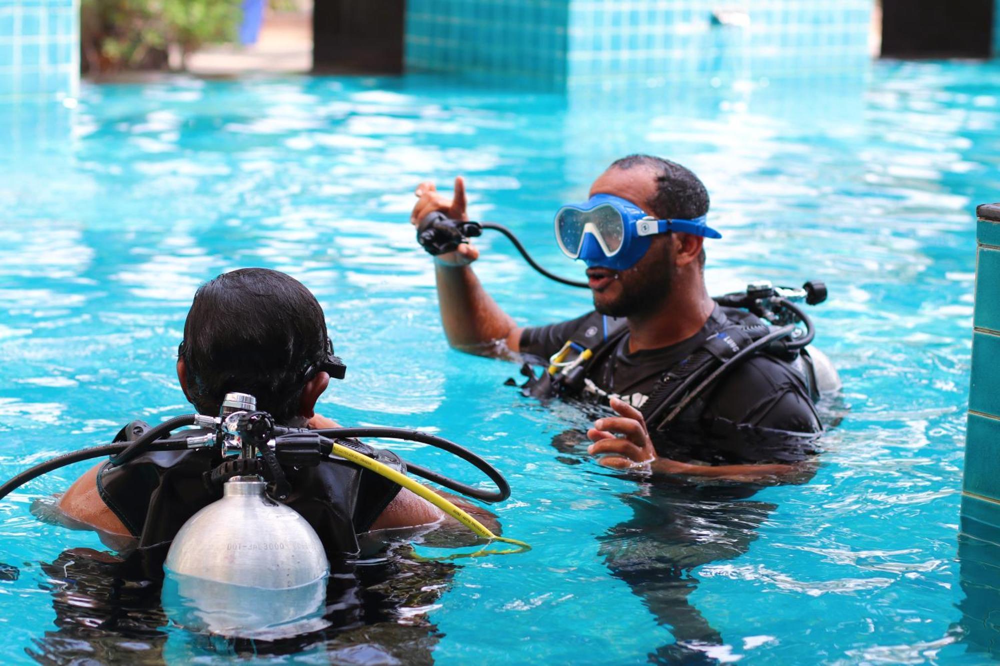 Lagoona Beach Luxury Resort And Spa Al Manamah Esterno foto The photo shows two divers in a pool. One diver is wearing a scuba mask and is speaking to the other diver, who is also equipped with scuba gear. They appear to be engaged in a discussion, possibly related to diving instructions or safety. The water 